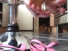 Feet playing with pink flip-flops close-up.